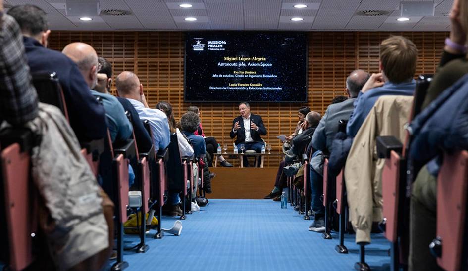 Un evento con un astronauta que da una charla a un público atento.