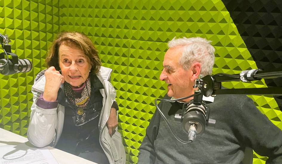 Dos personas conversan en un estudio de grabación con paredes verdes.