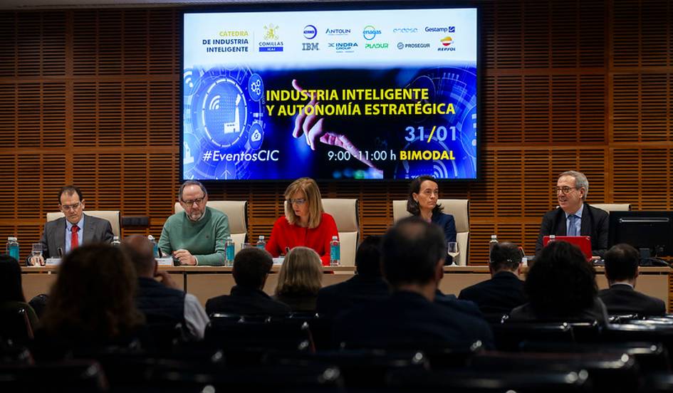 La imagen muestra un panel de discusión sobre industria inteligente y autonomía estratégica con varios ponentes frente a un público.