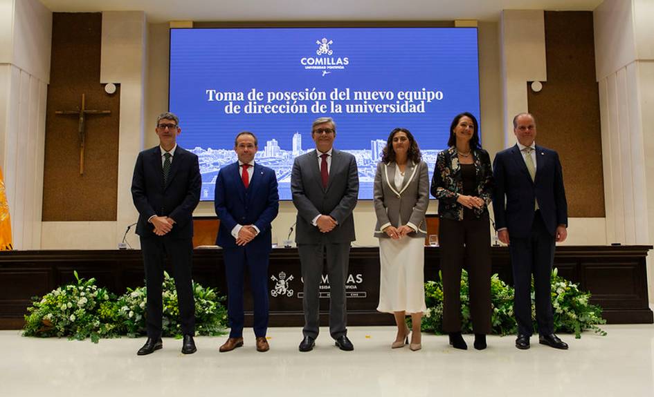 Grupo de seis personas de pie frente a un fondo con un cartel que anuncia la toma de posesión del nuevo equipo de dirección de la universidad Comillas.