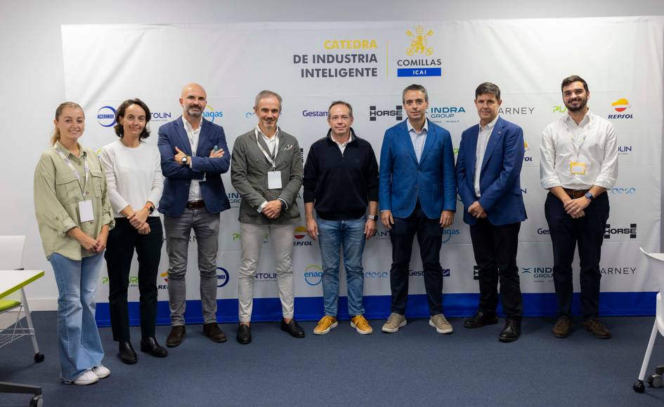 Un grupo de personas posando frente a una pared con logos de empresas y una pancarta sobre 'Industria Inteligente'.