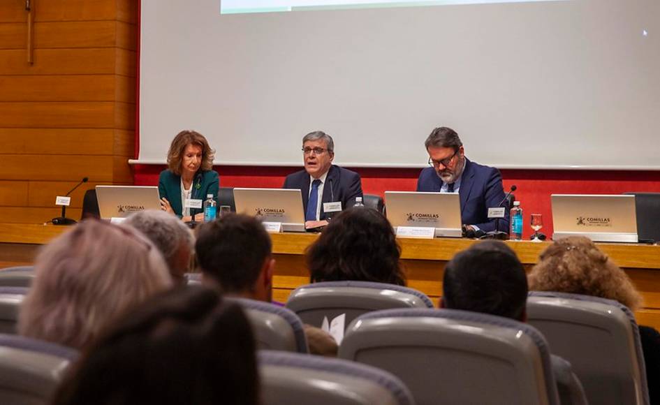 Una mesa redonda con tres ponentes discutiendo en una sala llena de audiencia.