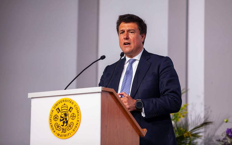 A man in a suit speaking at a podium with a university emblem