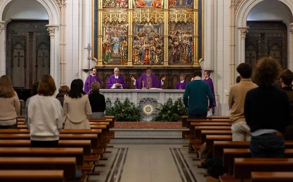 Personas asistiendo a una misa en una iglesia con un altar dorado al fondo.