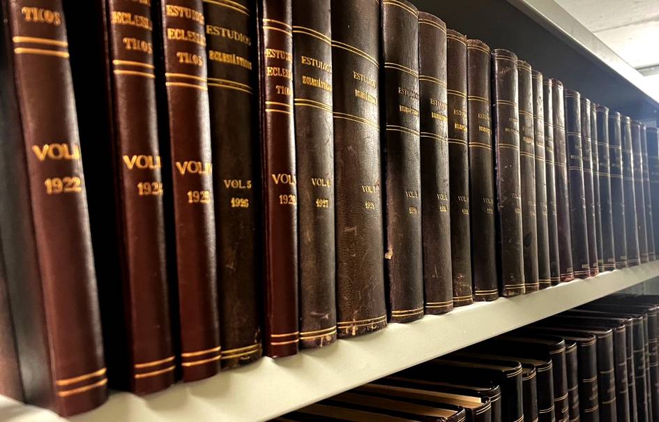 Una estantería con numerosos volúmenes de la revista Estudios Eclesiásticos encuadernados en cuero.