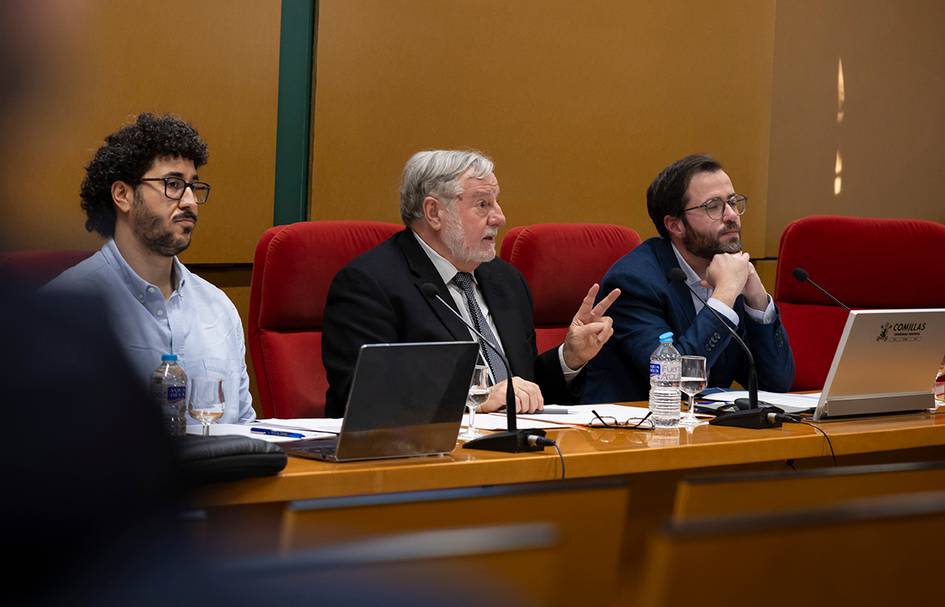 Tres hombres participan en una reunión formal en una sala con paredes naranjas.