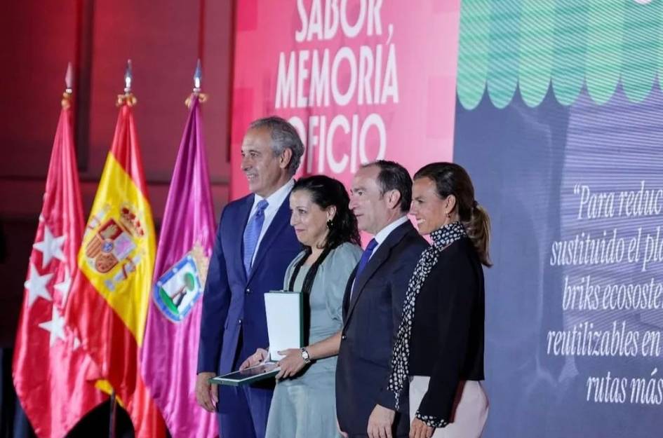 Un grupo de personas posando en un evento con banderas de fondo.
