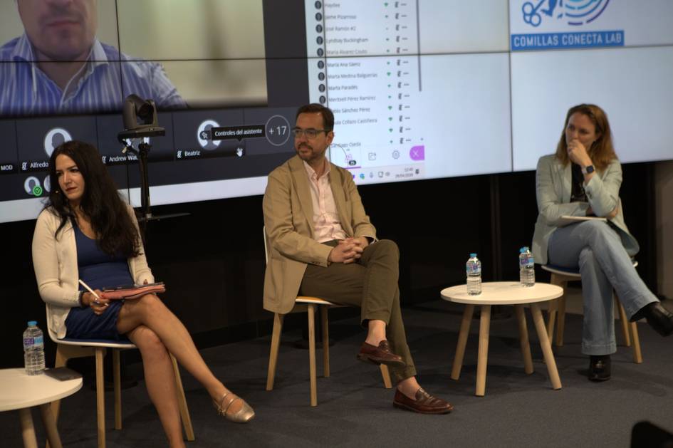 Una mesa redonda con tres ponentes, donde dos están presentes físicamente y uno aparece en una pantalla.