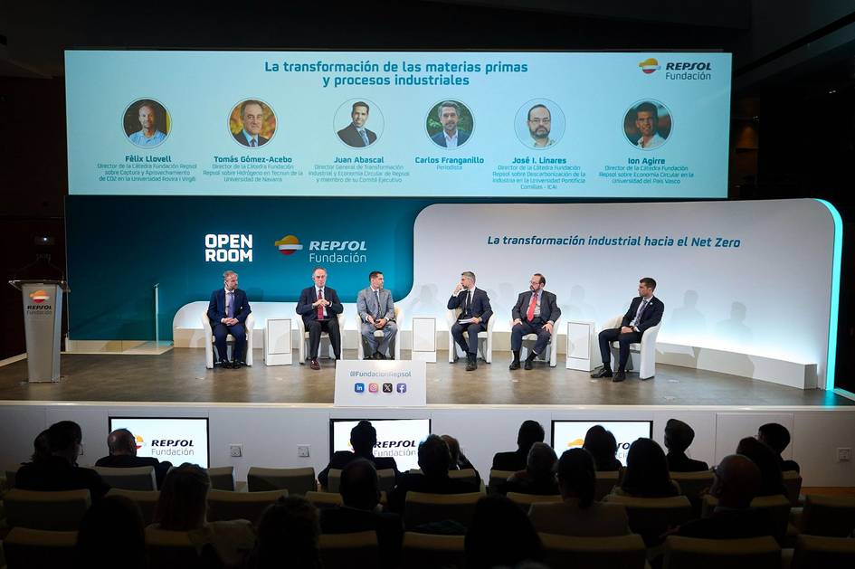 Several professionals seated on stage at a conference panel discussing industrial transformation towards net zero, with the audience in foreground.