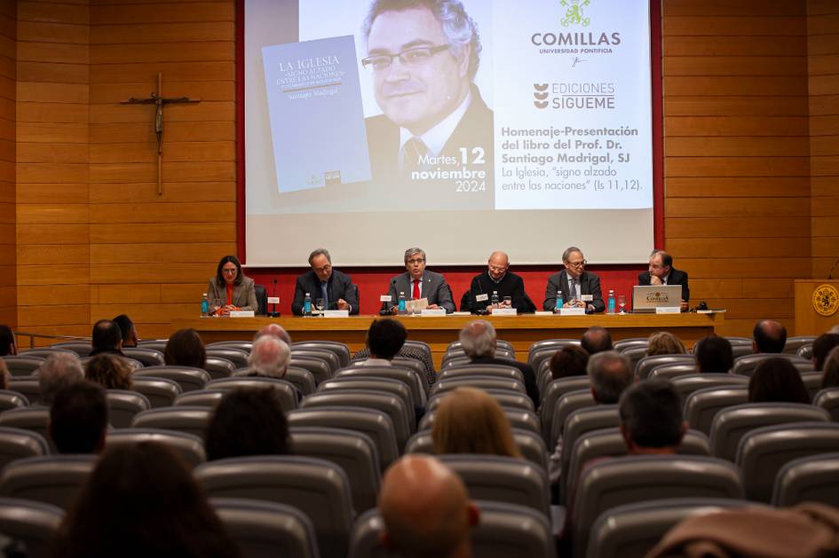 Personas sentadas en un panel durante un evento en una sala de conferencias con asistentes observando.