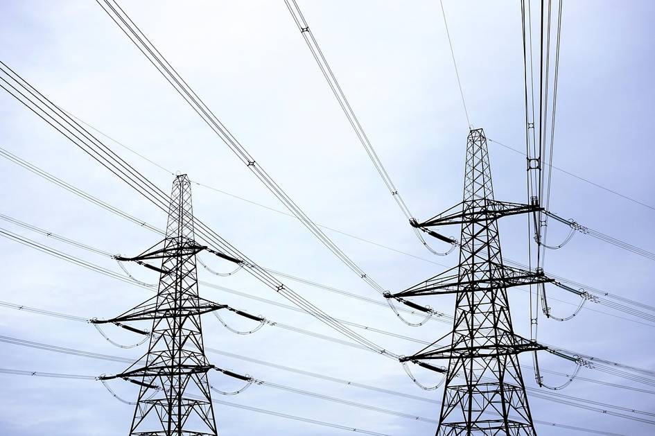 Imagen de torres de transmisión eléctrica bajo un cielo nublado.