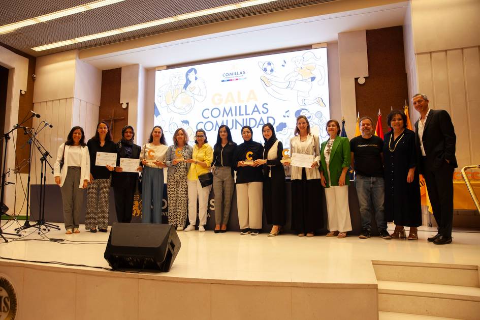 Group of people standing on a stage at an event, holding certificates.