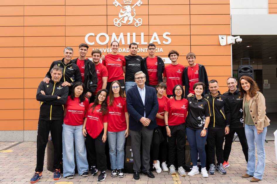 A group of people in sports attire and a few in casual clothes posing in front of the Comillas Pontifical University entrance.