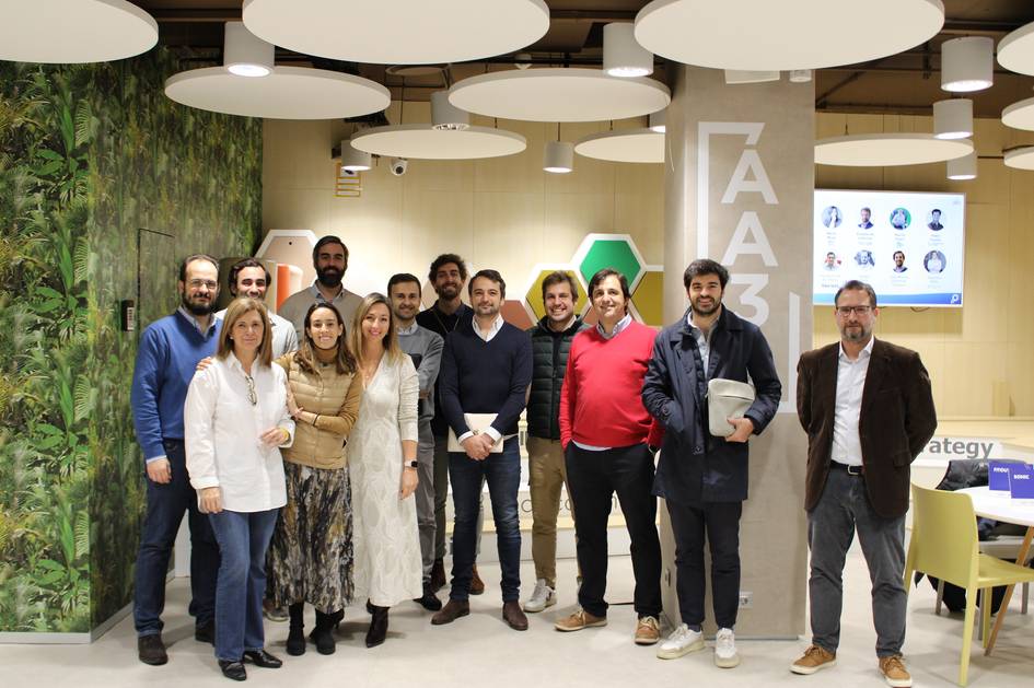 Grupo de personas sonrientes posando en una oficina moderna con decoración que incluye motivos de vegetación.