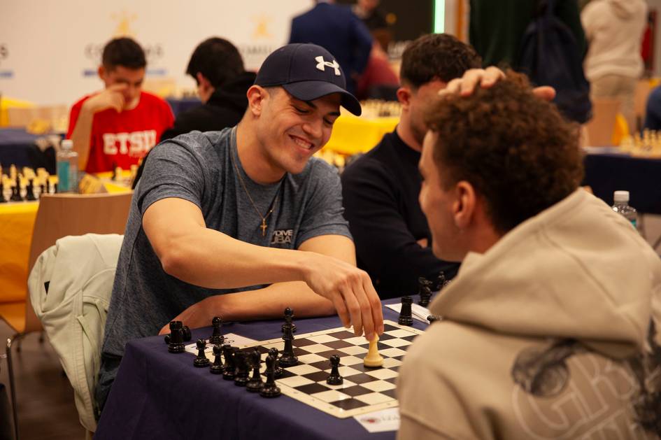 Dos jugadores de ajedrez compiten en un torneo, disfrutando del momento y colaborando en la partida.