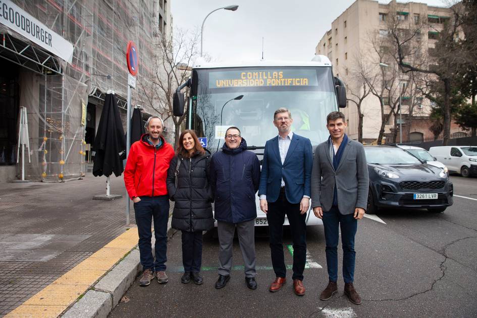 Grupo de personas posando frente a un autobús en una calle de la ciudad.