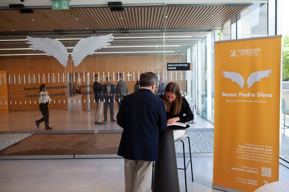 Una mujer y un hombre interactúan en un espacio moderno con un cartel sobre becas al fondo.
