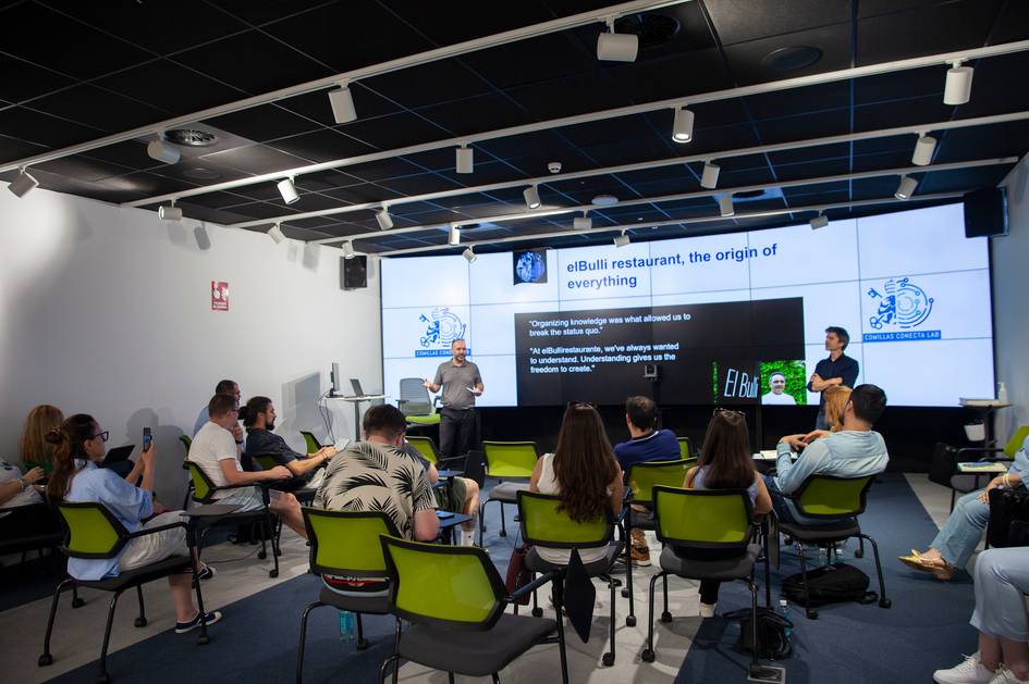 Un grupo de personas asisten a una charla sobre el restaurante elBulli en un ambiente moderno y tecnológico.