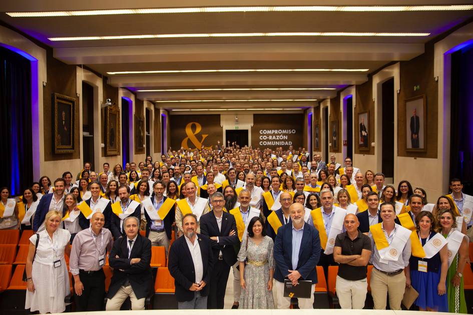 Una multitud de personas celebrando un evento con becas académicas en un salón.