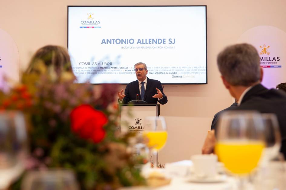 Un orador presenta en un evento de la Universidad Comillas mientras los asistentes lo observan desde la mesa.
