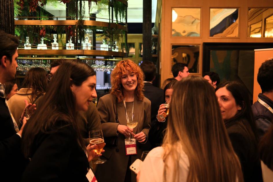 Un grupo de personas conversando animadamente en un evento social con bebidas en la mano.