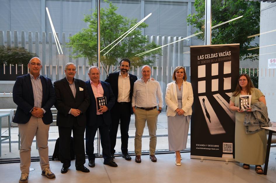 Un grupo de personas posando en un evento junto a un banner que presenta un libro llamado 'Las celdas vacías'.