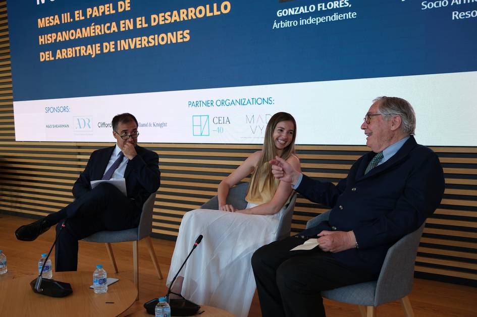 Una mesa de debatión donde tres personas conversan sobre arbitraje de inversiones en Hispanoamérica.