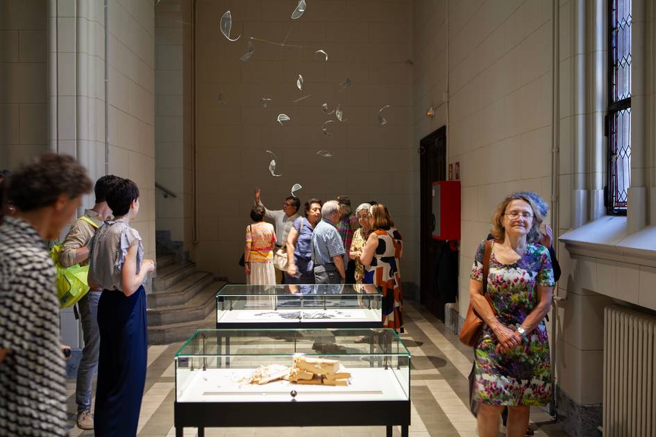 Una sala de museo con visitantes admirando las exposiciones y un grupo conversando.