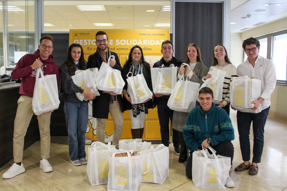 Un grupo de personas sonriendo en un recinto cerrado, sosteniendo bolsas de tela con un logo visible.