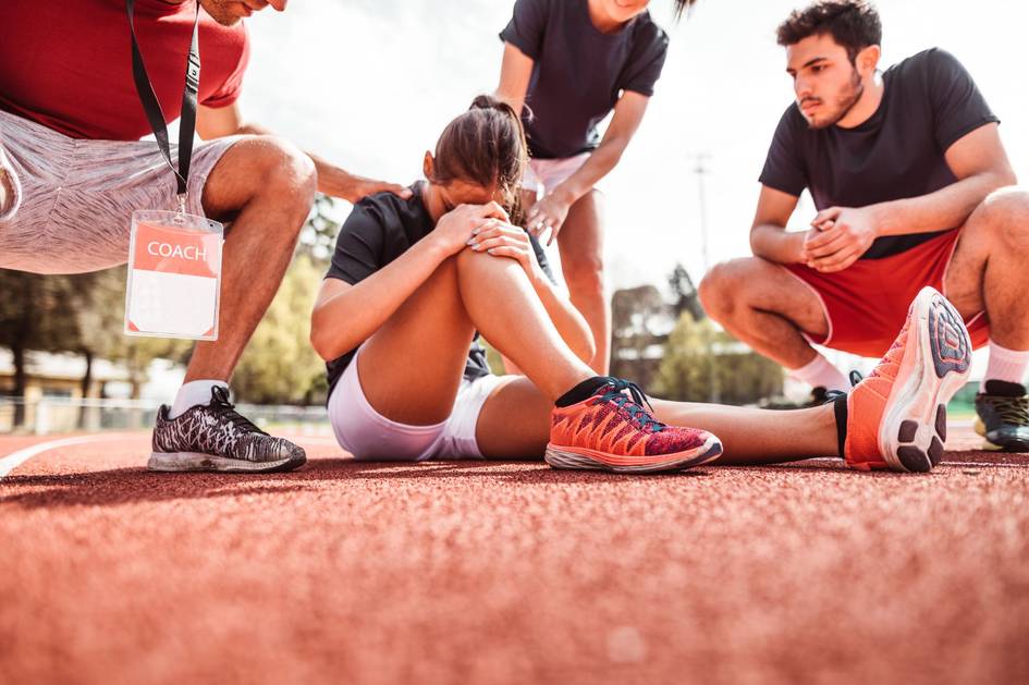 Un grupo de personas ayuda a una atleta que parece haber sufrido una lesión en la pista de atletismo.
