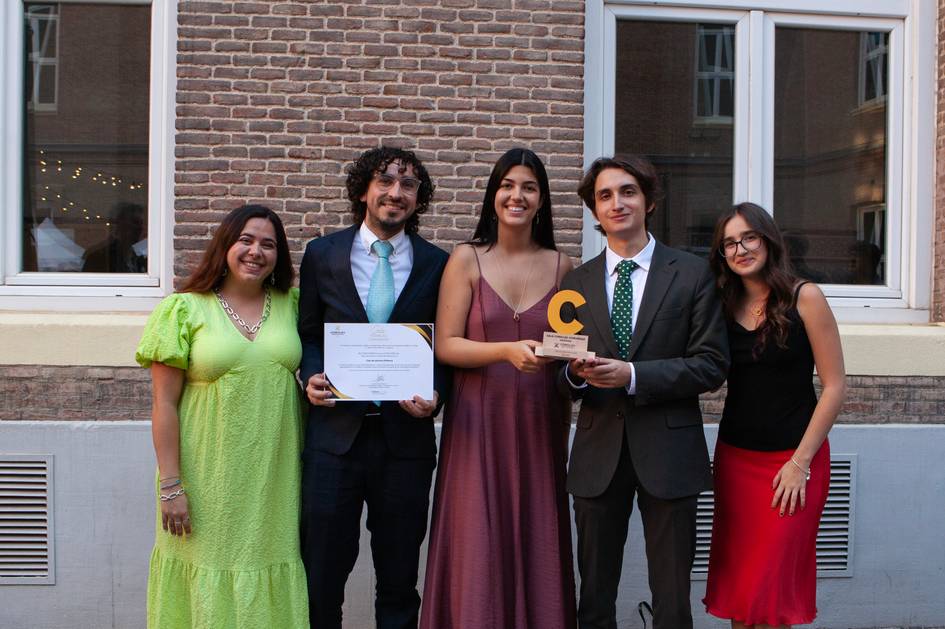 Un grupo de cinco personas posa sonriente después de recibir un reconocimiento en un evento formal.