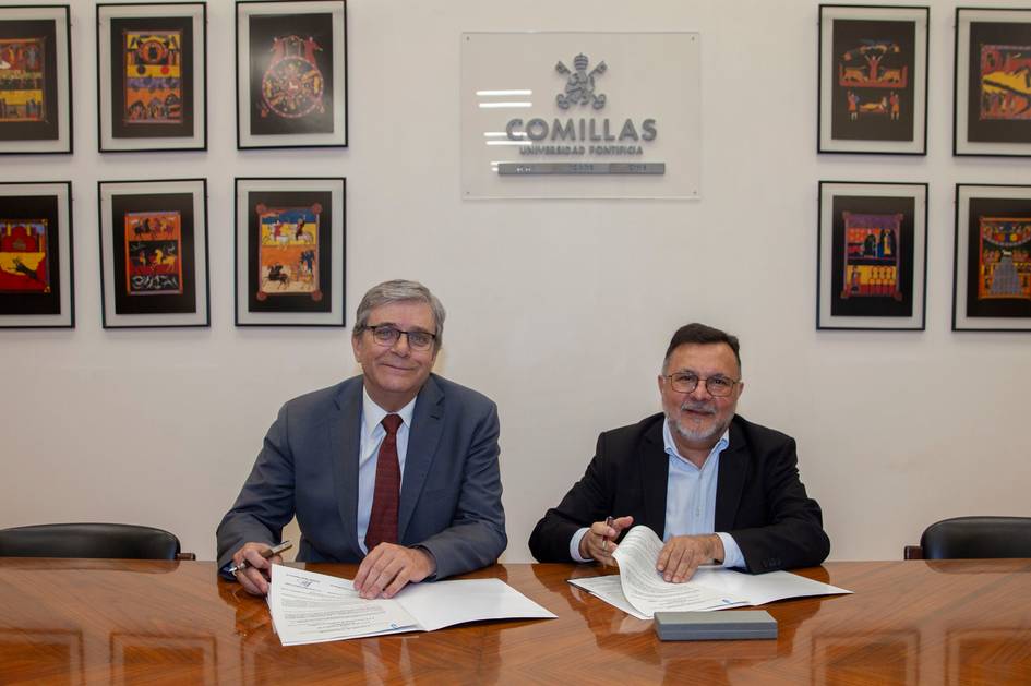 Dos hombres sentados en una mesa firmando documentos en un ambiente institucional.