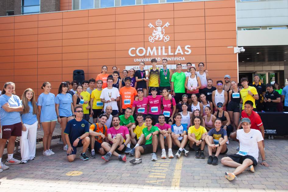 Un grupo de estudiantes de diferentes colores de camiseta se reúne frente a la Universidad Pontificia Comillas para una actividad deportiva.