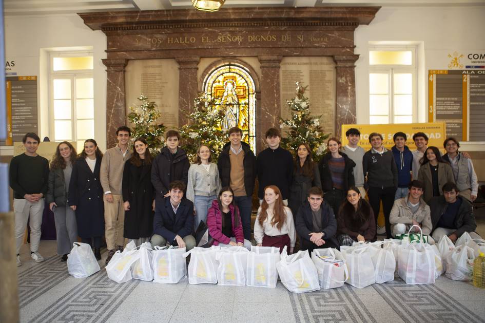 Grupo de personas posando frente a un altar decorado con árboles de Navidad y bolsas de regalo a sus pies.