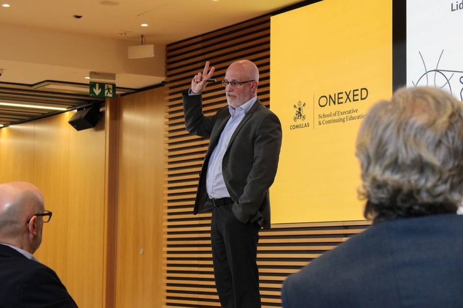 Un orador da una charla mientras los asistentes le prestan atención.