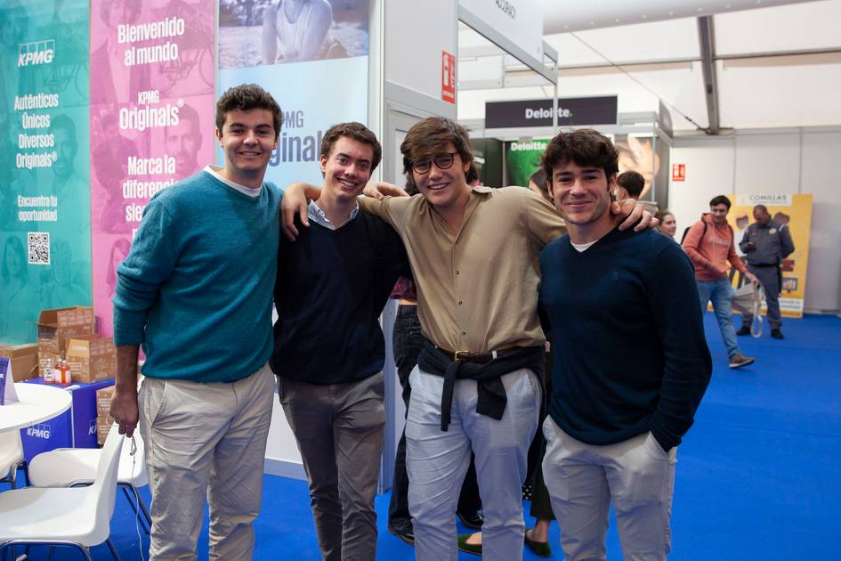 Four young men smiling and posing together at an indoor event, one dressed in a costume resembling a character from Star Wars.