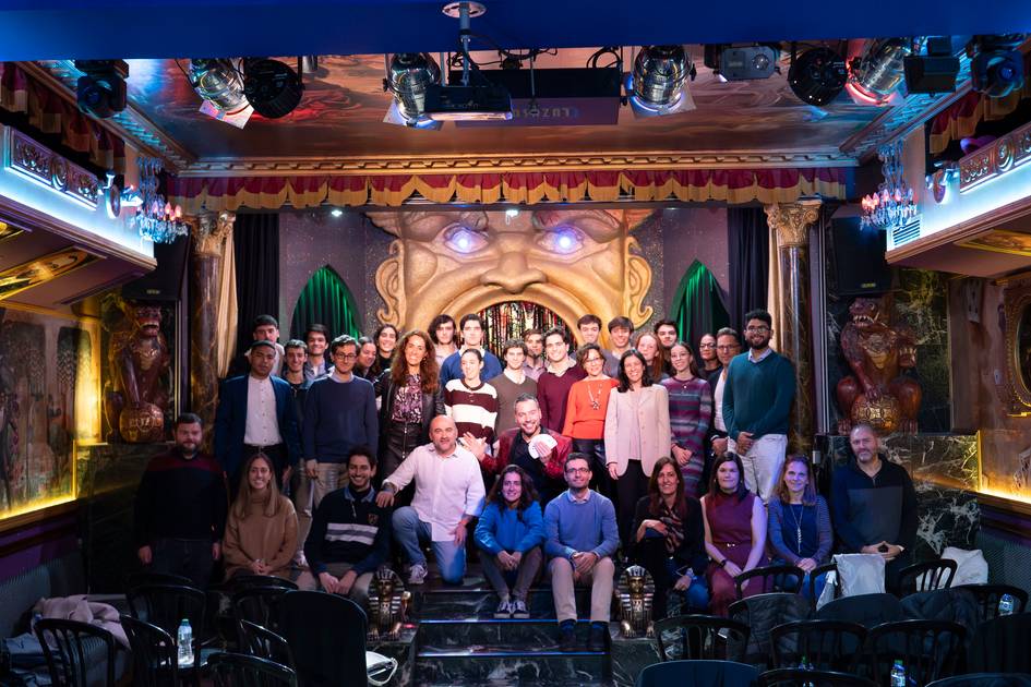 Un grupo de personas sonriendo en un teatro decorado con luces y detalles ornamentales.