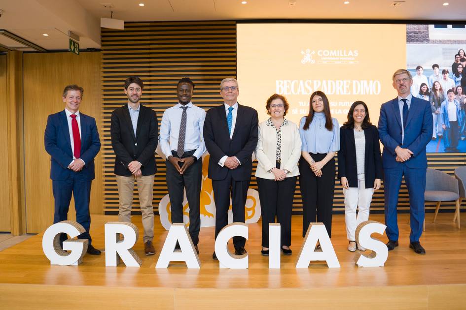 Un grupo de personas posando en un evento de entrega de becas en un auditorio.
