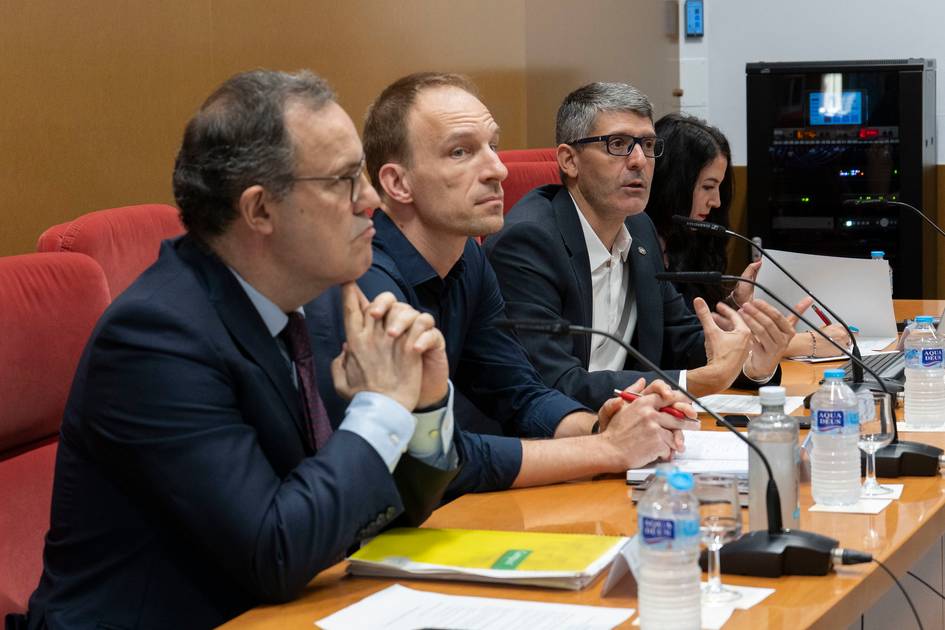 Cuatro personas sentadas en una mesa durante una reunión formal.