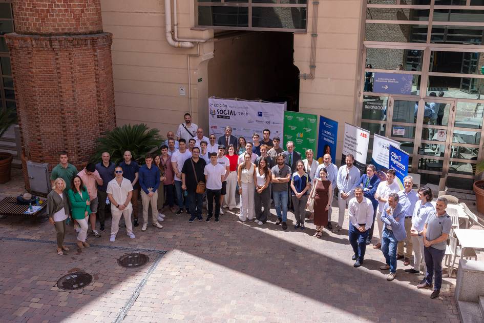 Un grupo grande de personas posando en un evento al aire libre frente a un edificio.