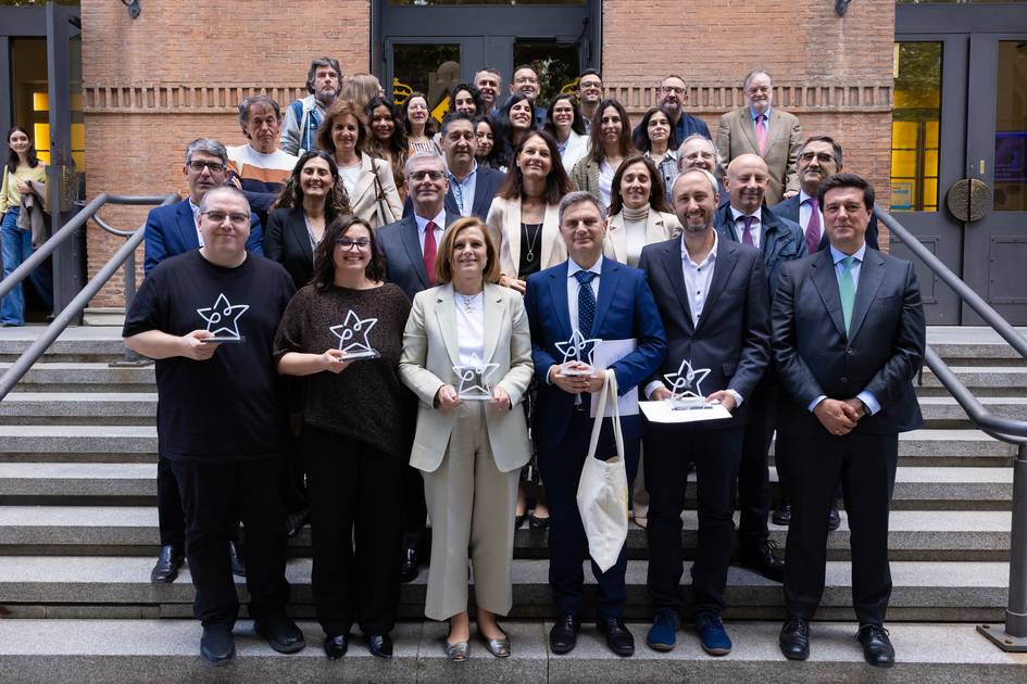 Un grupo de personas posando en un evento, sosteniendo trofeos en una escalera.