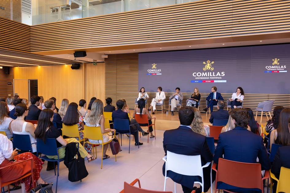 Un panel de discusión se lleva a cabo en un moderno auditorio con varias personas sentadas en la audiencia.