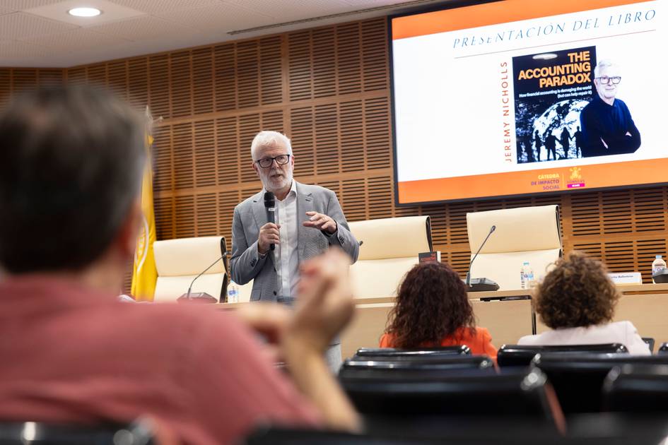 Una presentación de un libro en un auditorio, con un orador y un público atento.