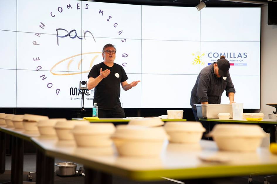 Two people giving a cooking presentation in front of an audience with the theme 'pan' displayed on a projector screen.