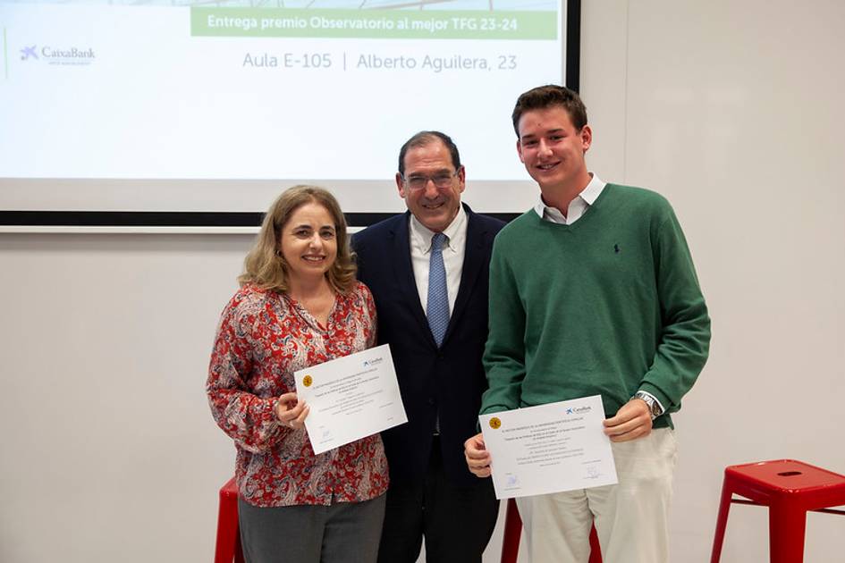 Three people are standing and posing for a photo at an award ceremony, holding certificates.