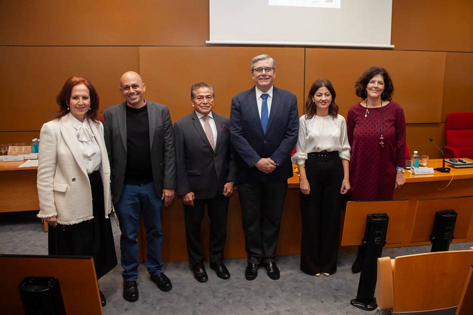 A group of six individuals, three men and three women, standing together in a conference room.