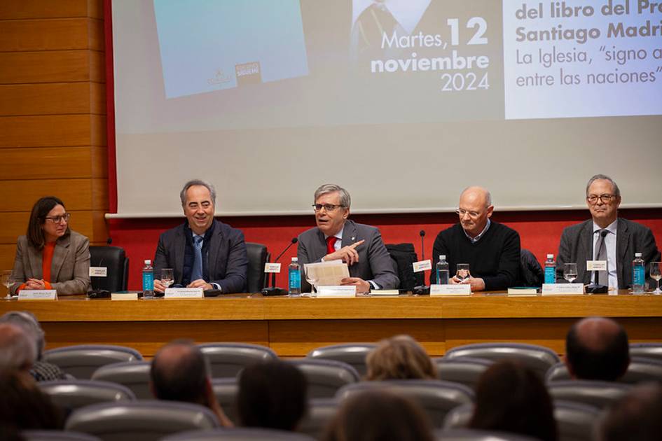 Un grupo de cinco personas se sienta en un panel de discusión en un auditorio.