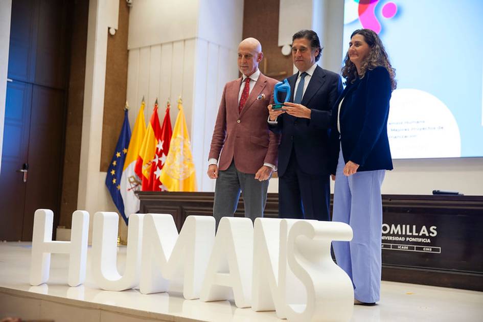 Tres personas posan en un escenario con un premio en un evento sobre humanos.