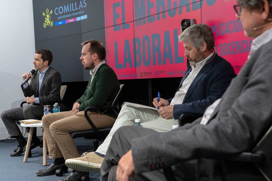 Un panel de discusión sobre el mercado laboral con varios ponentes en un auditorio.
