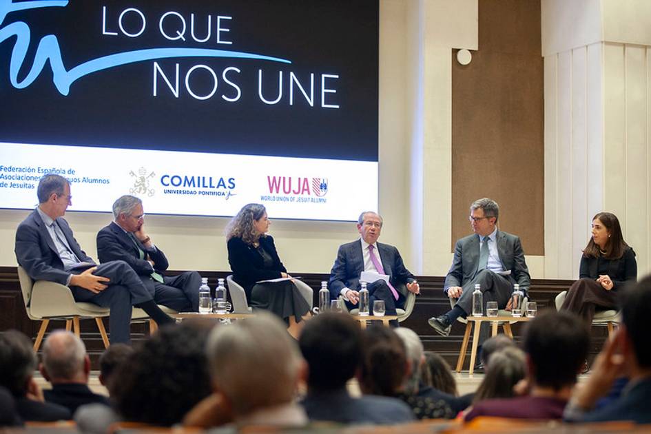 Un panel de discusión con varios ponentes sentados en un escenario frente a un público.
